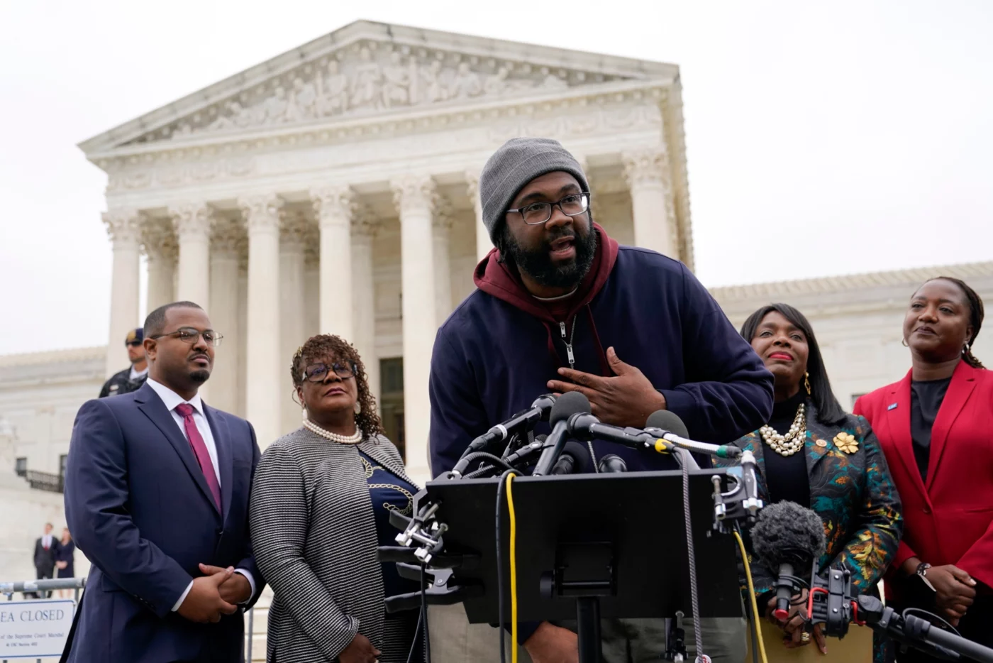 Evan Milligan, center, plaintiff in Allen v. Milligan, an Alabama redistricting case that could have far-reaching effects on minority voting power across the U.S., speaks with members of the press following oral arguments outside the U.S. Supreme Court on Capitol Hill in Washington, Tuesday, Oct. 4, 2022. Standing behind Milligan are Milligan's counsel Deuel Ross, from left, Letetia Jackson, Rep. Terri Sewell, D-Ala., and Janai Nelson, President and Director-Counsel of the NAACP Legal Defense Fund. (AP Photo/Patrick Semansky)