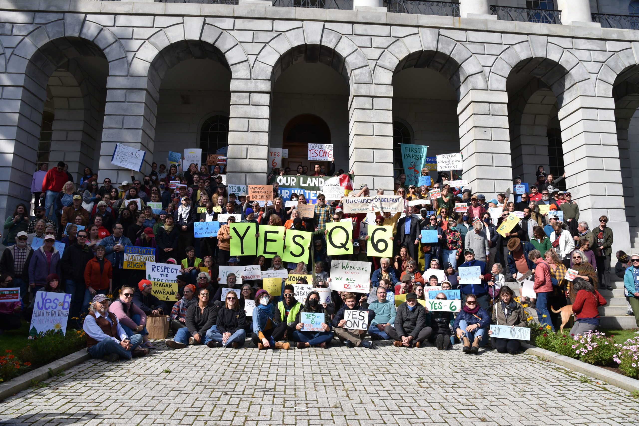 Group of people with sign that says YES Q6